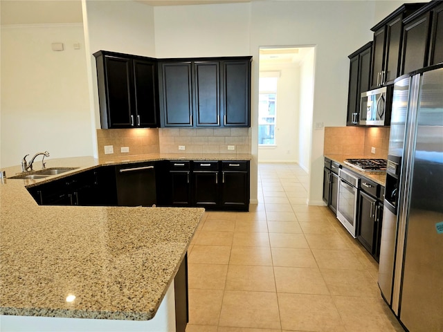 22106 Flashing Ridge Dr, Spring, TX 77389 - kitchen with appliances with stainless steel finishes, dark cabinets, light stone counters, light tile patterned floors, and crown molding