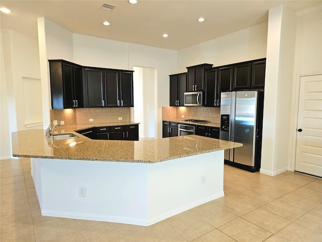 22106 Flashing Ridge Dr, Spring, TX 77389 - kitchen with appliances with stainless steel finishes, dark cabinetry, light stone counters, decorative backsplash, and recessed lighting