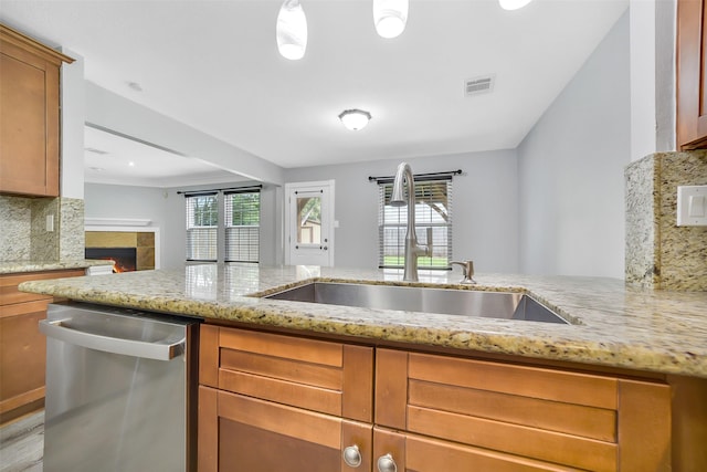 21614 Bowcreek Ln, Katy, TX 77449 - kitchen with dishwasher, backsplash, light stone counters, a tile fireplace, and brown cabinetry