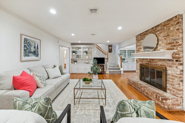 13307 Westport Ln, Houston, TX 77079 - living room featuring stairway, light wood finished floors, a brick fireplace, ornamental molding, and recessed lighting