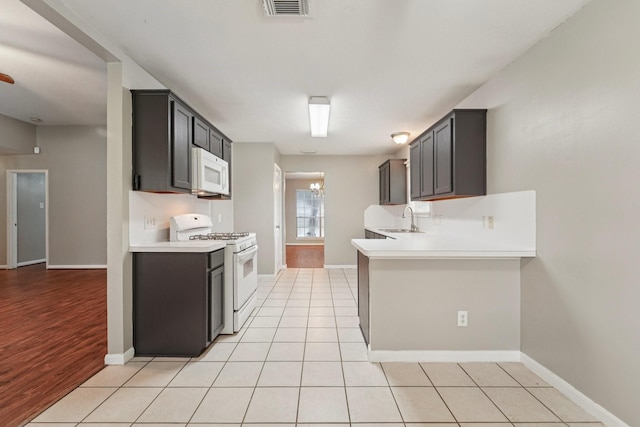 19115 Forest Ridge Dr, Magnolia, TX 77355 - kitchen featuring white appliances, light countertops, a peninsula, and light tile patterned flooring