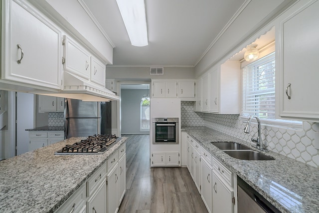 206 Enchanted River Dr, Spring, TX 77388 - kitchen with appliances with stainless steel finishes, white cabinets, wood finished floors, crown molding, and decorative backsplash