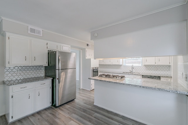 206 Enchanted River Dr, Spring, TX 77388 - kitchen featuring stainless steel appliances, white cabinetry, crown molding, backsplash, and light wood-style flooring