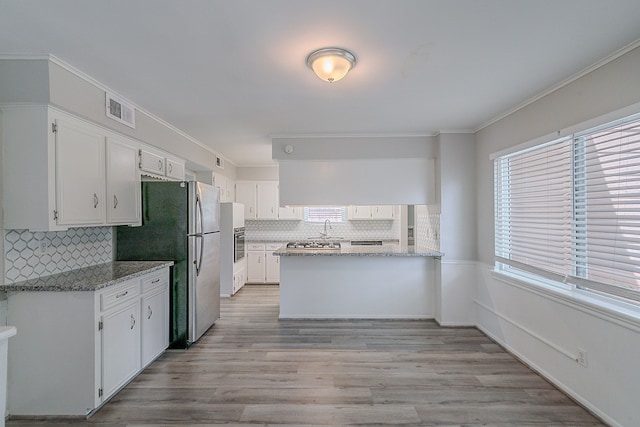 206 Enchanted River Dr, Spring, TX 77388 - kitchen featuring a peninsula, white cabinetry, backsplash, appliances with stainless steel finishes, and crown molding