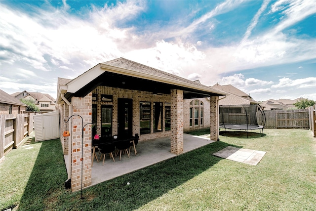 3319 Pleasant Hollow Ln, Houston, TX 77365 - back of house with a trampoline, a patio area, a fenced backyard, a storage unit, and brick siding