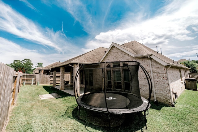 3319 Pleasant Hollow Ln, Houston, TX 77365 - rear view of house with a trampoline, brick siding, a fenced backyard, and a shingled roof