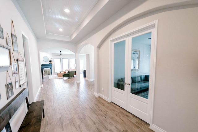 3319 Pleasant Hollow Ln, Houston, TX 77365 - corridor with french doors, arched walkways, light wood-type flooring, a tray ceiling, and recessed lighting