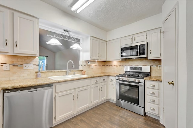 32 Sarita Rd, Angleton, TX 77515 - kitchen featuring stainless steel appliances, white cabinetry, wood finished floors, backsplash, and a textured ceiling