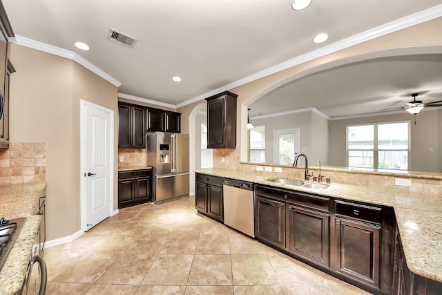 12131 Cove Ridge Ln, Cypress, TX 77433 - kitchen featuring appliances with stainless steel finishes, arched walkways, decorative backsplash, dark brown cabinets, and light stone counters