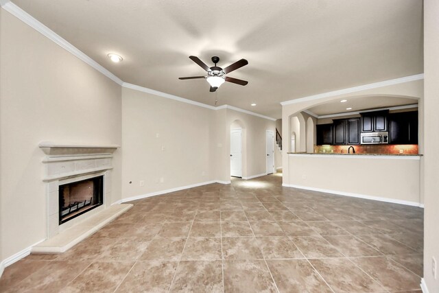 12131 Cove Ridge Ln, Cypress, TX 77433 - unfurnished living room with arched walkways, a ceiling fan, crown molding, a fireplace with raised hearth, and recessed lighting