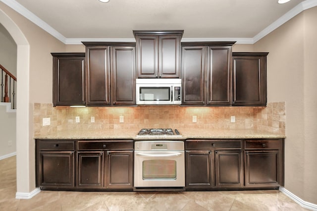 12131 Cove Ridge Ln, Cypress, TX 77433 - kitchen featuring appliances with stainless steel finishes, dark brown cabinetry, arched walkways, crown molding, and light stone countertops