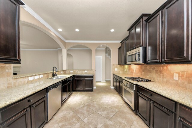 12131 Cove Ridge Ln, Cypress, TX 77433 - kitchen with appliances with stainless steel finishes, arched walkways, tasteful backsplash, dark brown cabinetry, and light tile patterned floors