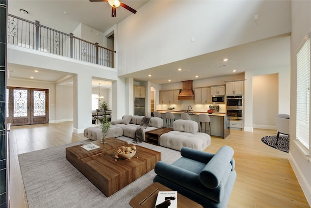 3242 N Upland St, Katy, TX 77493 - living room featuring a towering ceiling, light wood-style flooring, ceiling fan, and a chandelier