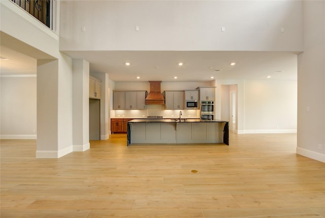 3242 N Upland St, Katy, TX 77493 - kitchen with stainless steel appliances, custom exhaust hood, open floor plan, light wood finished floors, and an island with sink
