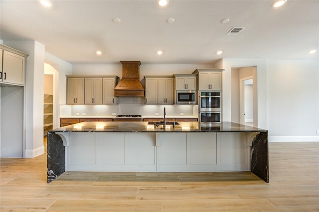 3242 N Upland St, Katy, TX 77493 - kitchen with stainless steel appliances, premium range hood, a large island with sink, dark stone counters, and a kitchen bar