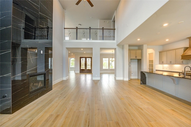 3242 N Upland St, Katy, TX 77493 - unfurnished living room featuring a ceiling fan, a fireplace, light wood-style flooring, a high ceiling, and recessed lighting