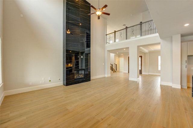 3242 N Upland St, Katy, TX 77493 - unfurnished living room featuring a towering ceiling, ceiling fan, stairway, a high end fireplace, and light wood-style floors