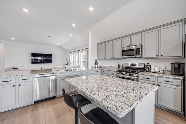 24107 Avocet Creek Rd, Katy, TX 77493 - kitchen with appliances with stainless steel finishes, gray cabinetry, lofted ceiling, light wood finished floors, and light stone counters