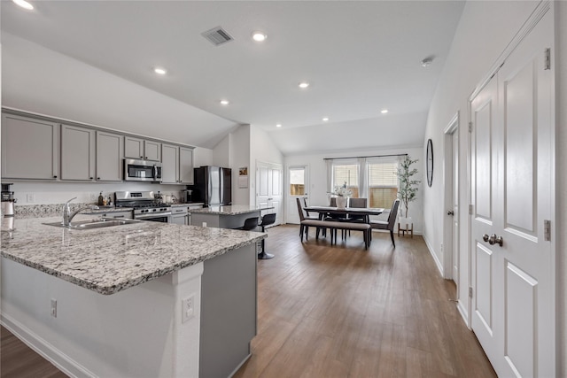 24107 Avocet Creek Rd, Katy, TX 77493 - kitchen with appliances with stainless steel finishes, gray cabinetry, lofted ceiling, a center island, and light stone counters