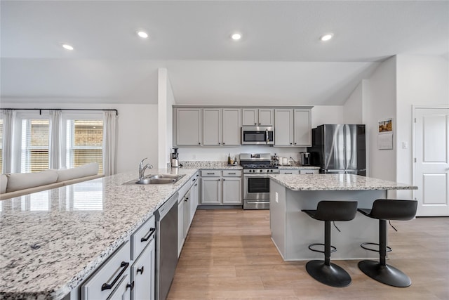 24107 Avocet Creek Rd, Katy, TX 77493 - kitchen with stainless steel appliances, vaulted ceiling, light wood-style floors, a peninsula, and a kitchen bar