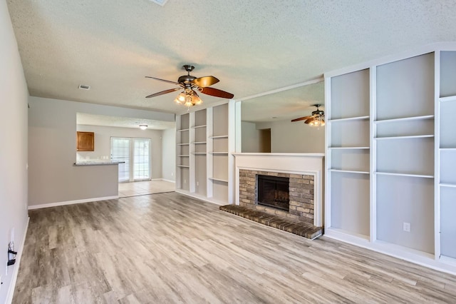 11910 Yearling Dr, Houston, TX 77065 - unfurnished living room featuring a textured ceiling, a ceiling fan, light wood-type flooring, and a fireplace with raised hearth