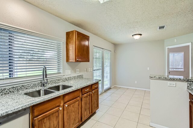 11910 Yearling Dr, Houston, TX 77065 - kitchen with dishwasher, light tile patterned flooring, a textured ceiling, light stone countertops, and brown cabinetry
