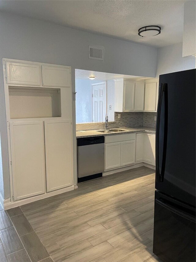 8703 Victorian Village Dr Unit 8703, Houston, TX 77071 - kitchen featuring freestanding refrigerator, stainless steel dishwasher, light wood-type flooring, white cabinets, and a textured ceiling