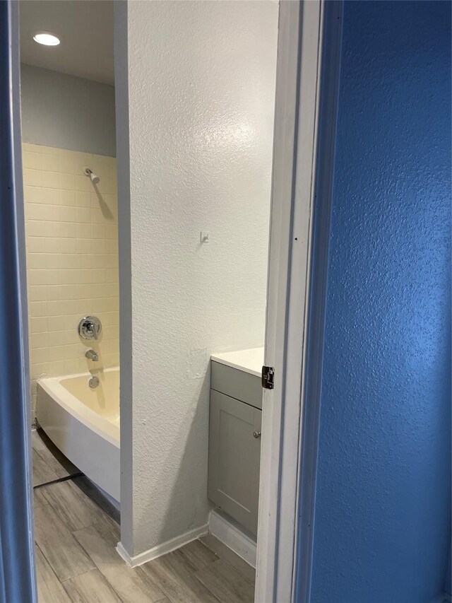 8703 Victorian Village Dr Unit 8703, Houston, TX 77071 - bathroom featuring wood finished floors, vanity, a textured wall, and washtub / shower combination