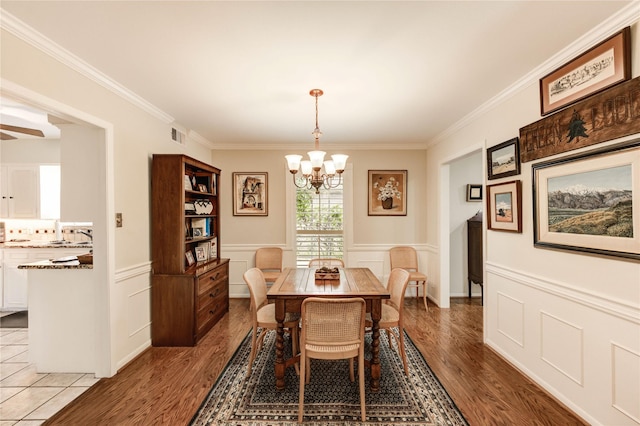2602 Briarbrook Dr, Houston, TX 77042 - dining area featuring a chandelier, crown molding, light wood-type flooring, a wainscoted wall, and a decorative wall