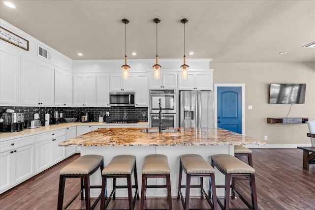 8307 Amber Cove Dr, Atascocita, TX 77346 - kitchen with appliances with stainless steel finishes, backsplash, dark wood-style flooring, white cabinetry, and recessed lighting