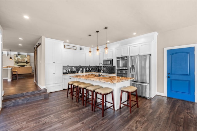8307 Amber Cove Dr, Atascocita, TX 77346 - kitchen featuring appliances with stainless steel finishes, backsplash, recessed lighting, dark wood-type flooring, and light stone counters
