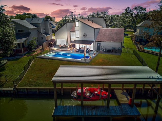 8307 Amber Cove Dr, Atascocita, TX 77346 - back of property at dusk with a fenced backyard, a water view, a residential view, and a patio