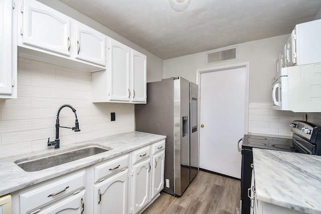 6915 Jeb Stuart Dr, Richmond, TX 77469 - kitchen featuring appliances with stainless steel finishes, backsplash, white cabinetry, and light wood finished floors
