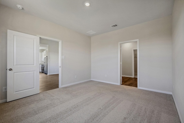 10419 Red Cardinal Dr, Houston, TX 77328 - unfurnished bedroom featuring carpet floors, baseboards, freestanding refrigerator, and a walk in closet