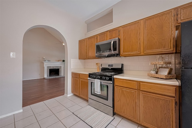 5814 N Magazine Cir, Houston, TX 77084 - kitchen featuring stainless steel appliances, light countertops, light tile patterned flooring, backsplash, and arched walkways