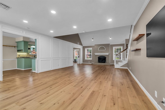 17427 Pinewood Forest Dr, Spring, TX 77379 - unfurnished living room with light wood-style flooring, stairs, lofted ceiling, a brick fireplace, and recessed lighting