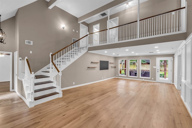 17427 Pinewood Forest Dr, Spring, TX 77379 - unfurnished living room with a towering ceiling, light wood-type flooring, stairway, a chandelier, and ceiling fan