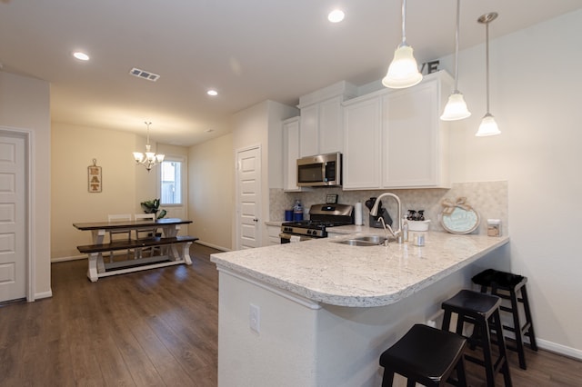 5529 Evanston Ln, Pasadena, TX 77505 - kitchen with stainless steel appliances, white cabinets, decorative backsplash, dark wood-style flooring, and a chandelier
