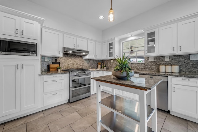 2539 Addison Rd, Houston, TX 77030 - kitchen featuring appliances with stainless steel finishes, under cabinet range hood, light tile patterned floors, backsplash, and white cabinetry