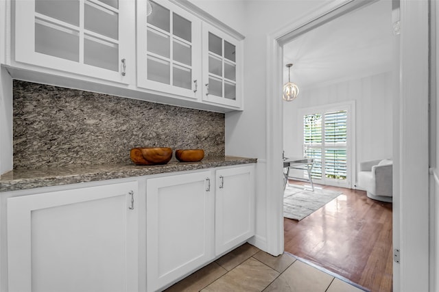 2539 Addison Rd, Houston, TX 77030 - kitchen with glass insert cabinets, white cabinets, decorative backsplash, and dark stone countertops