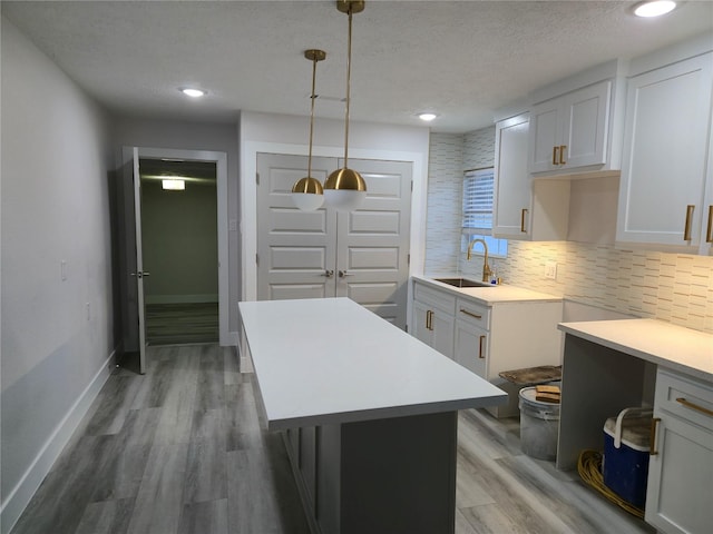 4104 Idaho St, Houston, TX 77021 - kitchen featuring light countertops, a textured ceiling, light wood finished floors, tasteful backsplash, and hanging light fixtures