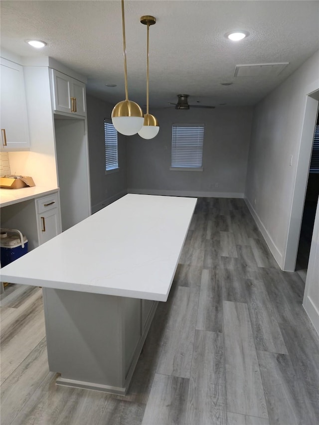 4104 Idaho St, Houston, TX 77021 - kitchen with wood finished floors, light countertops, a center island, hanging light fixtures, and a textured ceiling