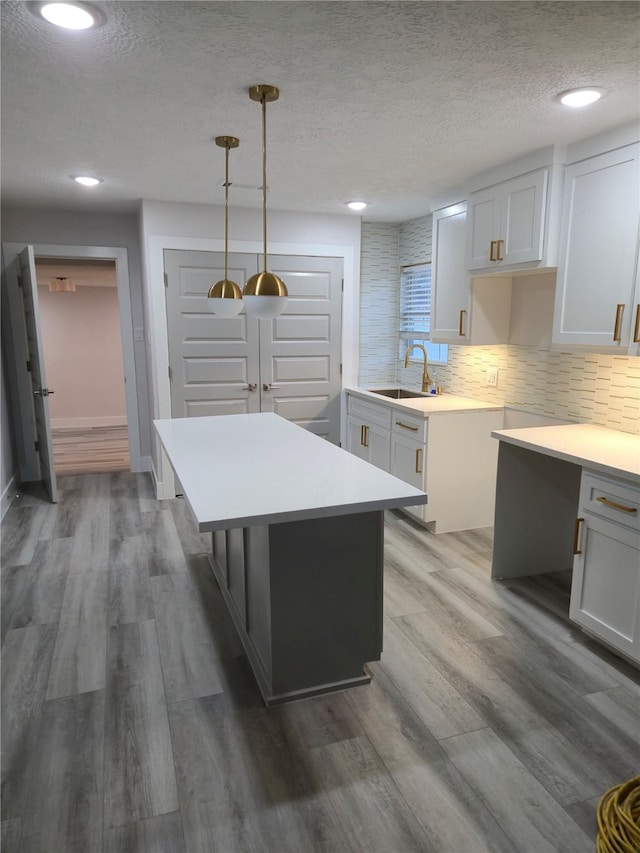 4104 Idaho St, Houston, TX 77021 - kitchen with a textured ceiling, backsplash, wood finished floors, a kitchen island, and hanging light fixtures