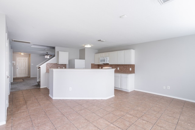 12026 Madison Oak St, Houston, TX 77038 - kitchen featuring white microwave, refrigerator, tasteful backsplash, white cabinetry, and light tile patterned floors