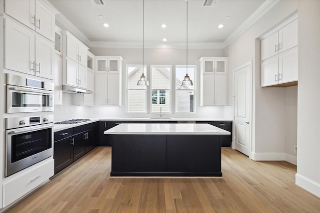 11057 Chatterton Dr, Houston, TX 77043 - kitchen with white cabinetry, gas cooktop, dark cabinets, ornamental molding, and a center island