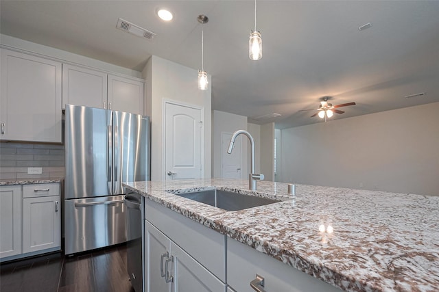 3414 Signor Dr, Houston, TX 77025 - kitchen featuring appliances with stainless steel finishes, dark wood finished floors, ceiling fan, light stone counters, and hanging light fixtures