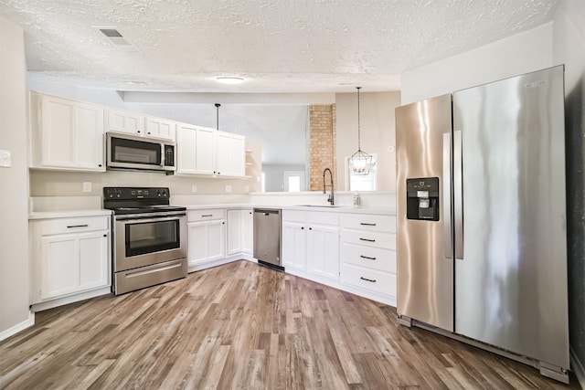 15806 Pfeiffer Dr, Houston, TX 77082 - kitchen featuring stainless steel appliances, a textured ceiling, light countertops, white cabinetry, and light wood-style floors
