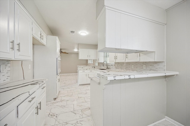 8210 Morley St, Houston, TX 77061 - kitchen with light marble finish floors, a peninsula, white cabinetry, and white oven