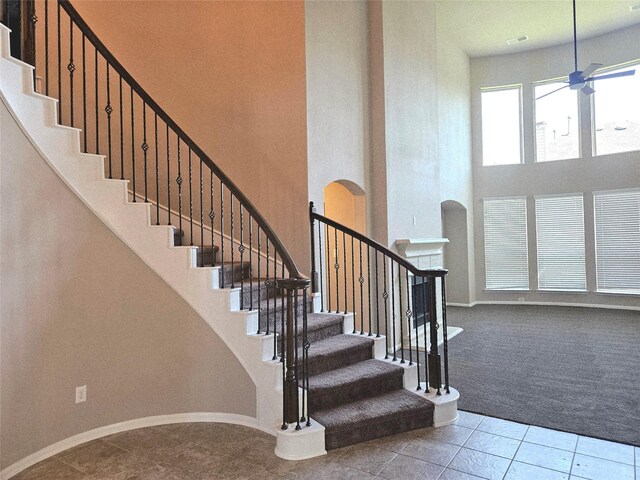 3811 Pearl Pass Ln, Sugar Land, TX 77479 - stairway featuring a high ceiling, carpet, tile patterned flooring, a ceiling fan, and arched walkways