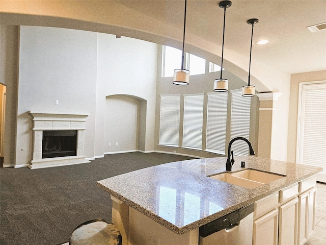 3811 Pearl Pass Ln, Sugar Land, TX 77479 - kitchen featuring stainless steel dishwasher, light stone countertops, a fireplace with raised hearth, pendant lighting, and carpet flooring